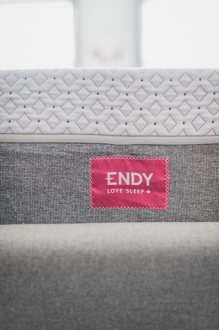 services-01 Close-up of modern Endy mattress with a pink tag, highlighting texture.