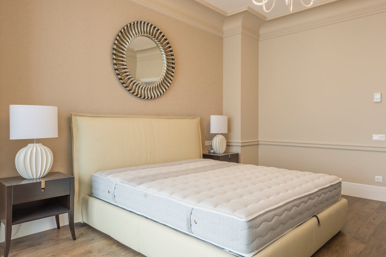 our-experience Spacious bedroom featuring modern decor, elegant lighting, and a plush bed with neutral tones.